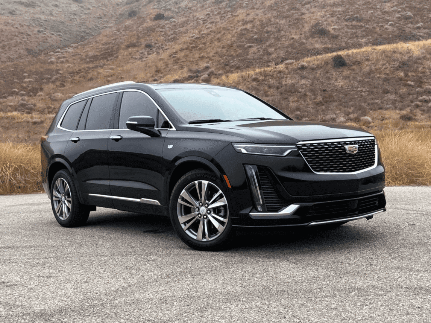 A black cadillac suv is parked on the side of a road.
