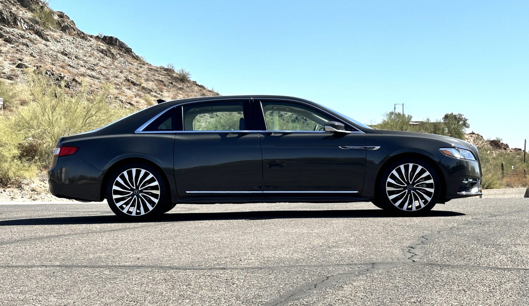 A black car is parked on the side of a road.