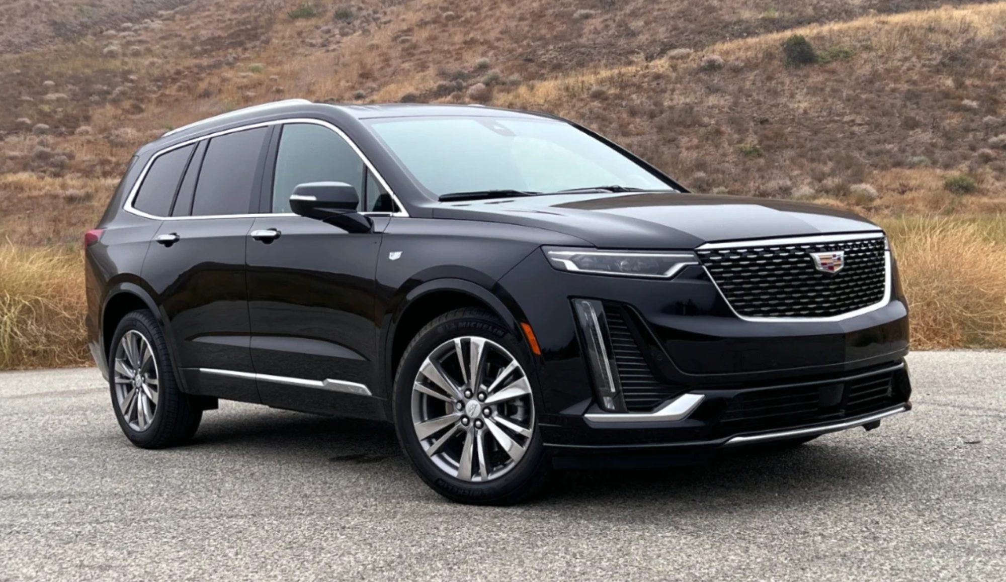 A black cadillac suv is parked on the side of a road.
