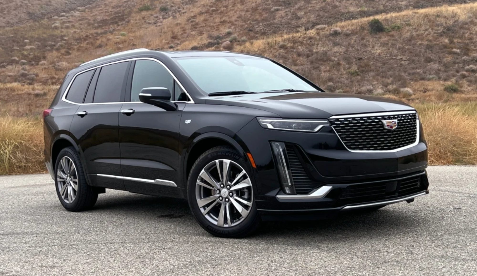 A black cadillac suv is parked on the side of a road.